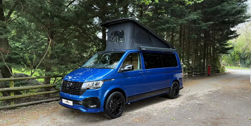 Blue Woodstock Campers conversion with the roof up in woodland